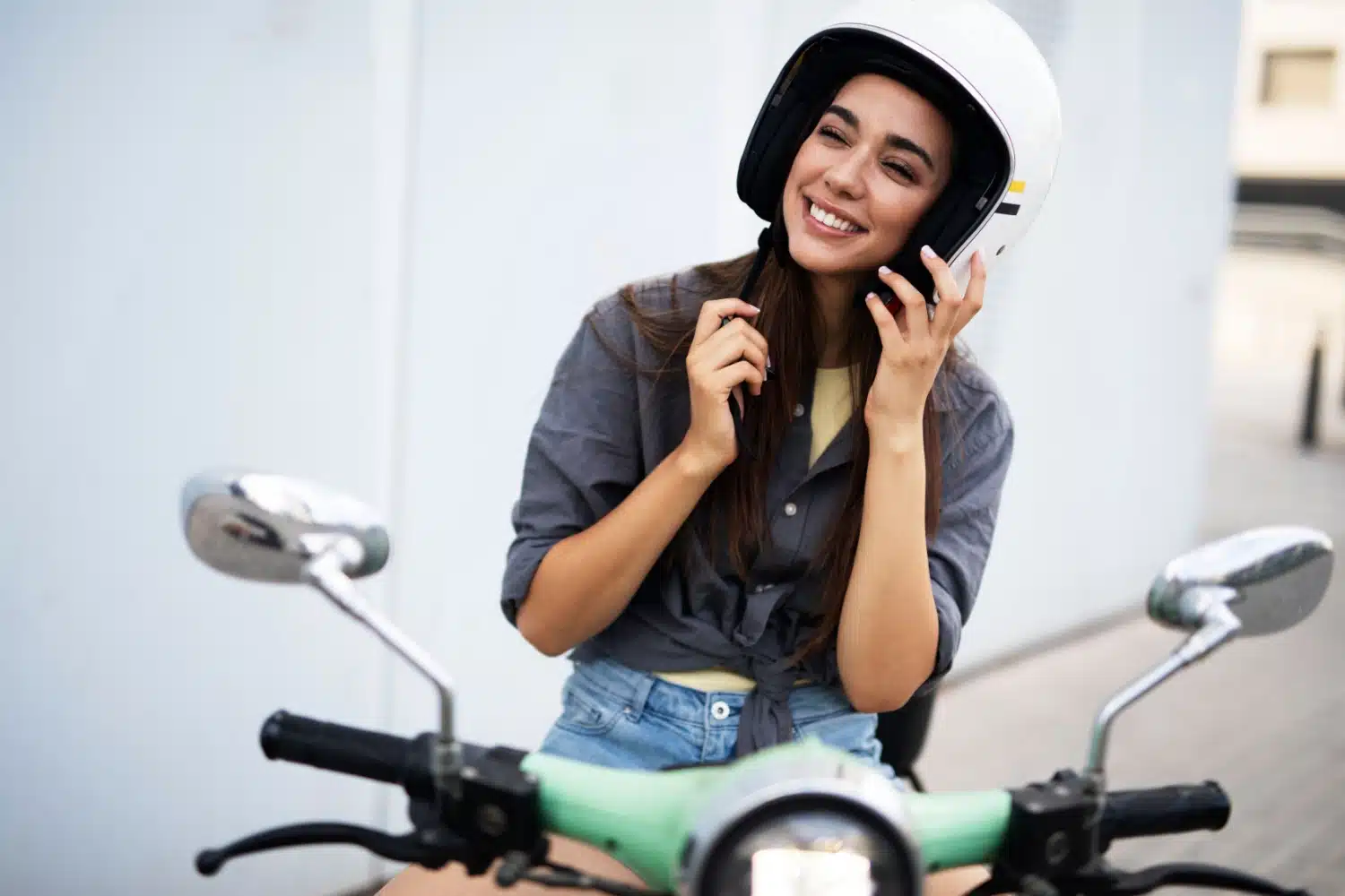 Kvinne på scooter som tar på seg hjelm